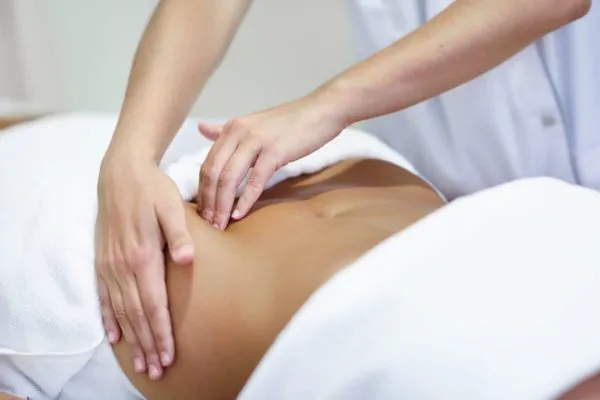 Woman receiving a belly massage at spa salon Female patient is receiving treatment by professional osteopathy therapist. Woman receiving a belly massage at spa salon